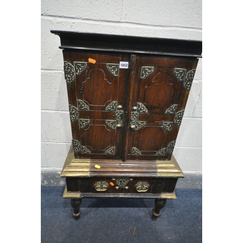 1652 - AN ANTIQUE HARDWOOD AND BRASS BANDED TWO DOOR CABINET, likely to be far Eastern, on a base with a si... 