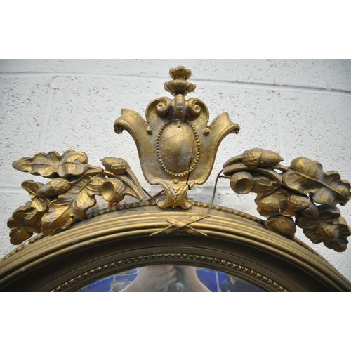 1655 - A REGENCY GILTWOOD CONVEX WALL MIRROR, the surmount with Lobed leaves and acorns surrounding a scrol... 