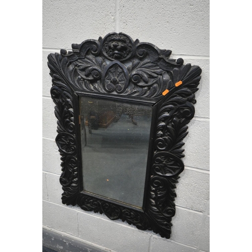 1658 - A 19TH CENTURY EBONISED CARVED OAK WALL MIRROR, with lions mask and foliate decoration, and bevelled... 