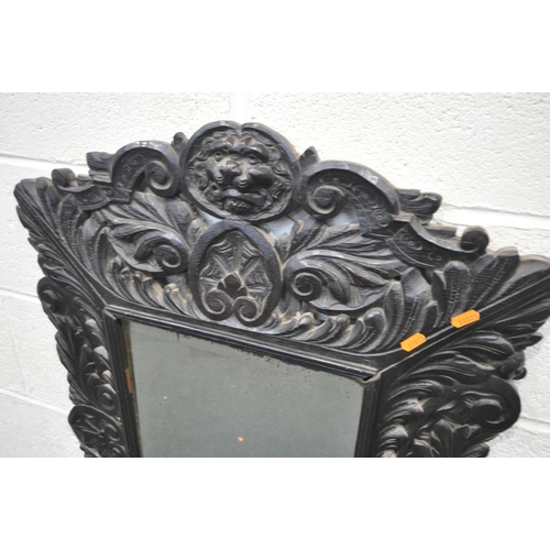 1658 - A 19TH CENTURY EBONISED CARVED OAK WALL MIRROR, with lions mask and foliate decoration, and bevelled... 