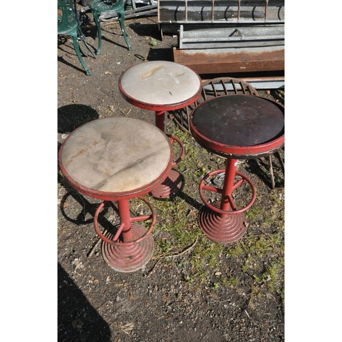 1205 - THREE ART DECO RED PAINTED METAL HIGH STOOLS, with a circular top, and footrest, on a stepped base, ... 