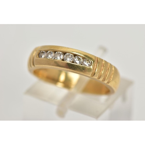 32 - A YELLOW METAL DIAMOND RING, wide band measuring approximately 4.7mm, designed with a row of channel... 