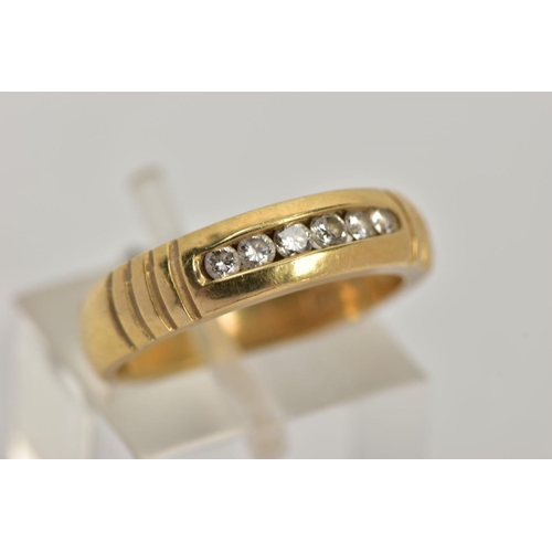 32 - A YELLOW METAL DIAMOND RING, wide band measuring approximately 4.7mm, designed with a row of channel... 