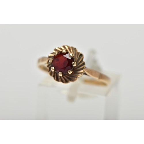 52 - A 9CT YELLOW GOLD GARNET SINGLE STONE RING, set with a circular cut garnet, within a textured border... 