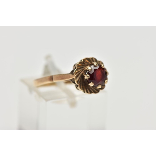 52 - A 9CT YELLOW GOLD GARNET SINGLE STONE RING, set with a circular cut garnet, within a textured border... 