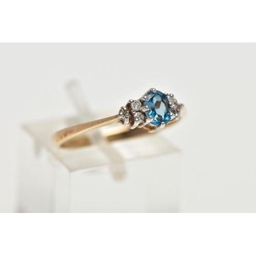 56 - A 9CT YELLOW GOLD TOPAZ AND DIAMOND DRESS RING, set with a principal oval cut blue topaz, flanked to... 