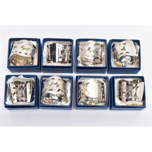 73 - A SET OF EIGHT SILVER NAPKIN RINGS, each designed with a pierced foliate motif with undulating rim, ... 