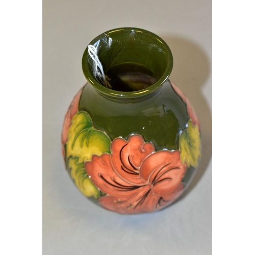 494 - A MOORCROFT POTTERY BALUSTER VASE DECORATED WITH CORAL HIBISCUS, on a green ground, impressed marks ... 