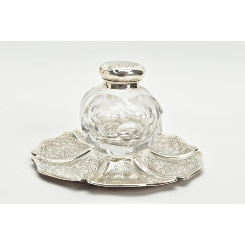 49 - A VICTORIAN SILVER AND GLASS INKWELL ON STAND, of wavy circular outline, foliate engraved decoration... 