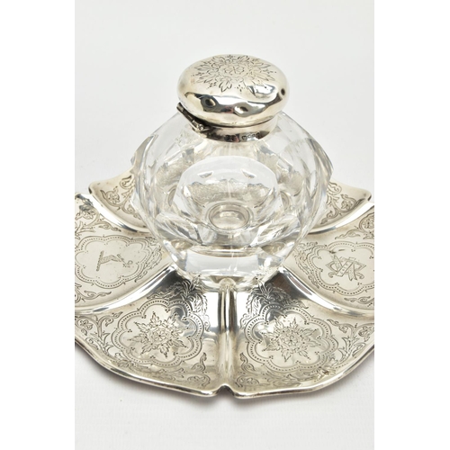 49 - A VICTORIAN SILVER AND GLASS INKWELL ON STAND, of wavy circular outline, foliate engraved decoration... 