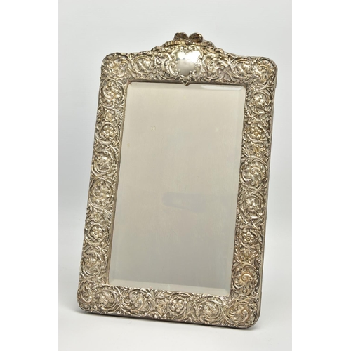 50 - AN EDWARDIAN SILVER MOUNTED EASEL BACK MIRROR, embossed with a ribbon over a vacant cartouche, pierc... 