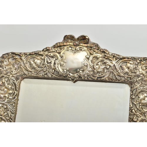 50 - AN EDWARDIAN SILVER MOUNTED EASEL BACK MIRROR, embossed with a ribbon over a vacant cartouche, pierc... 