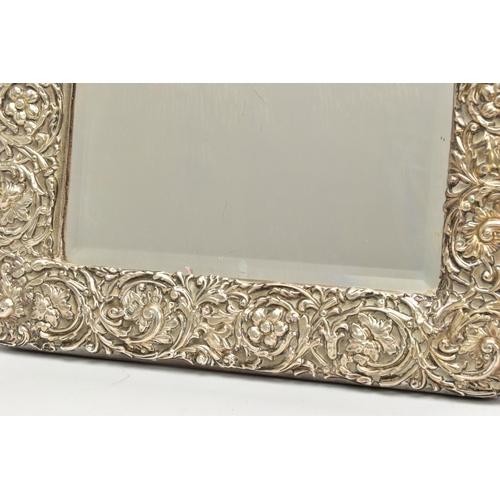 50 - AN EDWARDIAN SILVER MOUNTED EASEL BACK MIRROR, embossed with a ribbon over a vacant cartouche, pierc... 