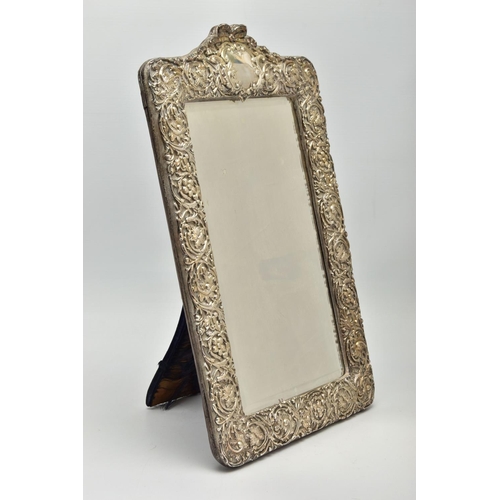 50 - AN EDWARDIAN SILVER MOUNTED EASEL BACK MIRROR, embossed with a ribbon over a vacant cartouche, pierc... 