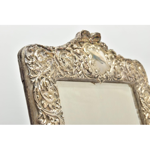 50 - AN EDWARDIAN SILVER MOUNTED EASEL BACK MIRROR, embossed with a ribbon over a vacant cartouche, pierc... 