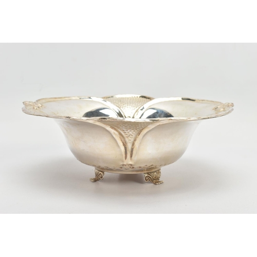 63 - AN EARLY 20TH CENTURY STYLE WHITE METAL WAVY RIMMED BOWL, repousse decoration, on three feet, the un... 