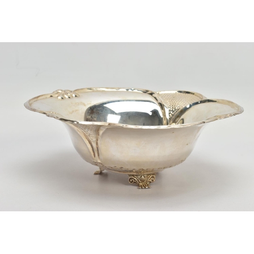 63 - AN EARLY 20TH CENTURY STYLE WHITE METAL WAVY RIMMED BOWL, repousse decoration, on three feet, the un... 