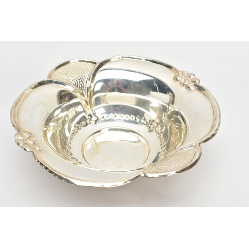 63 - AN EARLY 20TH CENTURY STYLE WHITE METAL WAVY RIMMED BOWL, repousse decoration, on three feet, the un... 