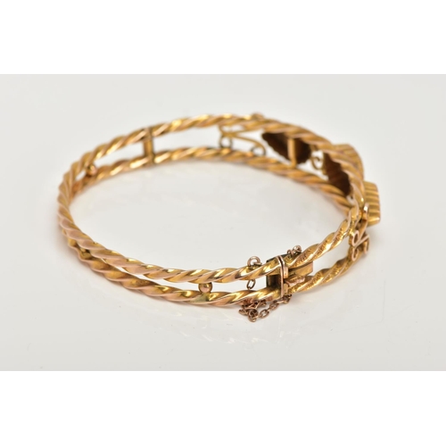 8 - AN EDWARDIAN 9CT GOLD HINGED BANGLE, designed with two textured yellow rope twist bands set apart wi... 