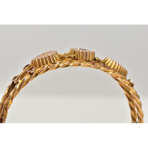 8 - AN EDWARDIAN 9CT GOLD HINGED BANGLE, designed with two textured yellow rope twist bands set apart wi... 