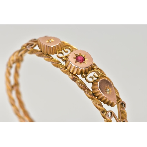 8 - AN EDWARDIAN 9CT GOLD HINGED BANGLE, designed with two textured yellow rope twist bands set apart wi... 