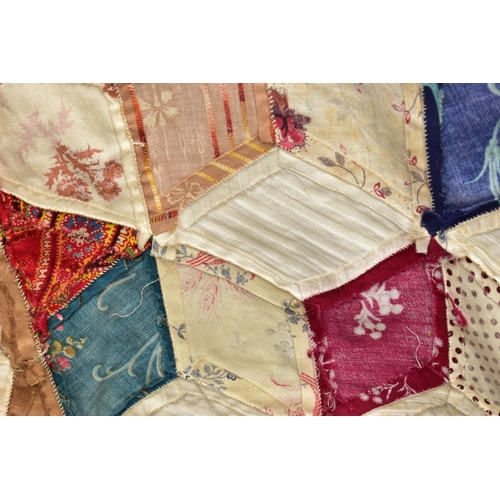 216 - A HAND STITCHED PATCHWORK QUILT, the geometric design incorporating fabrics which appear to be both ... 