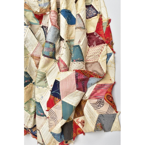 216 - A HAND STITCHED PATCHWORK QUILT, the geometric design incorporating fabrics which appear to be both ... 