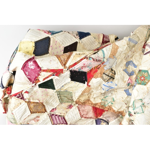 216 - A HAND STITCHED PATCHWORK QUILT, the geometric design incorporating fabrics which appear to be both ... 