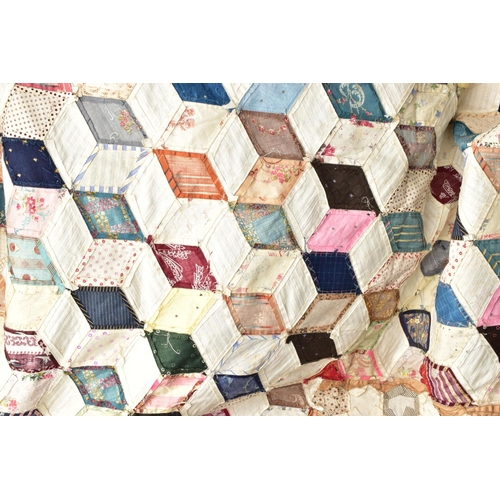 216 - A HAND STITCHED PATCHWORK QUILT, the geometric design incorporating fabrics which appear to be both ... 