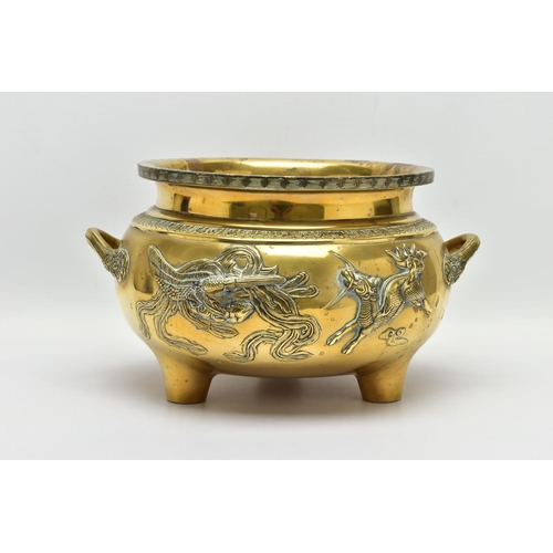 277 - A CHINESE BRASS TWIN HANDLED TRIPOD CENSER OF CIRCULAR FORM, cast in relief with four dragons, the i... 