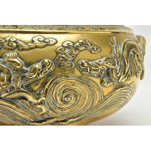 277 - A CHINESE BRASS TWIN HANDLED TRIPOD CENSER OF CIRCULAR FORM, cast in relief with four dragons, the i... 