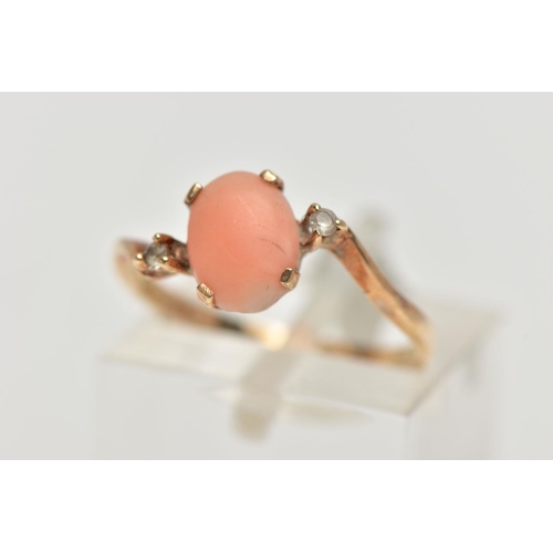 15 - A YELLOW METAL CORAL AND CUBIC ZIRCONIA RING, the oval coral cabochon, with asymmetric colourless sp... 
