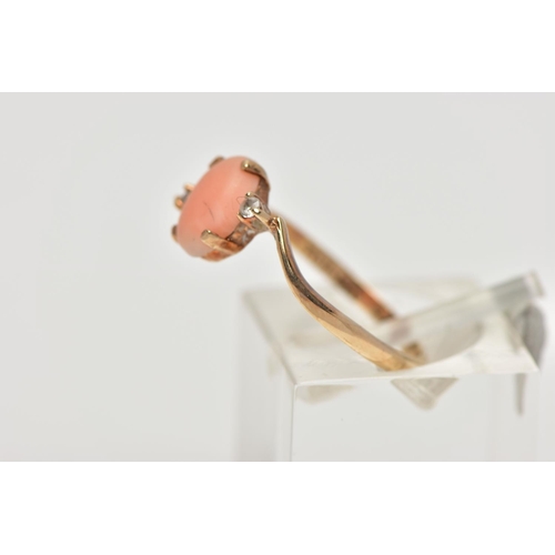 15 - A YELLOW METAL CORAL AND CUBIC ZIRCONIA RING, the oval coral cabochon, with asymmetric colourless sp... 