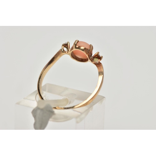 15 - A YELLOW METAL CORAL AND CUBIC ZIRCONIA RING, the oval coral cabochon, with asymmetric colourless sp... 