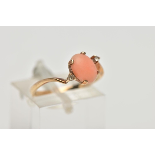 15 - A YELLOW METAL CORAL AND CUBIC ZIRCONIA RING, the oval coral cabochon, with asymmetric colourless sp... 