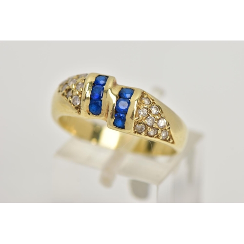 25 - A YELLOW METAL GEM SET RING, designed with two asymmetrical rows of three circular cut synthetic blu... 