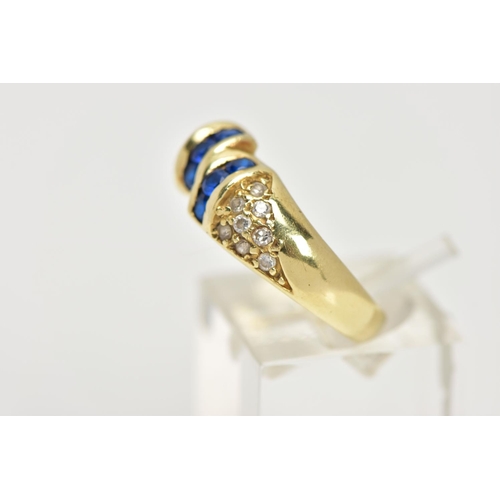 25 - A YELLOW METAL GEM SET RING, designed with two asymmetrical rows of three circular cut synthetic blu... 