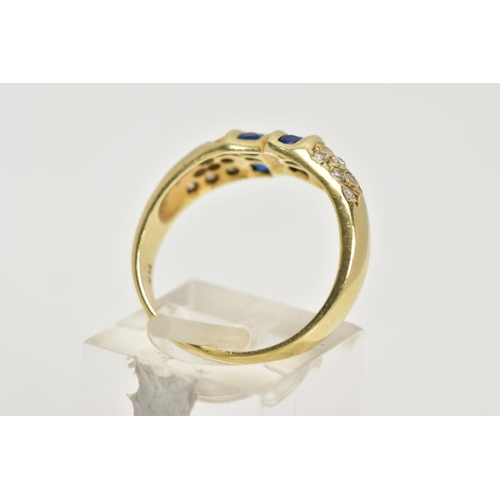 25 - A YELLOW METAL GEM SET RING, designed with two asymmetrical rows of three circular cut synthetic blu... 