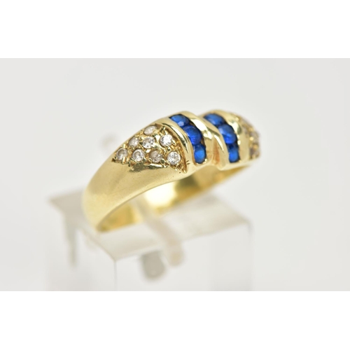 25 - A YELLOW METAL GEM SET RING, designed with two asymmetrical rows of three circular cut synthetic blu... 