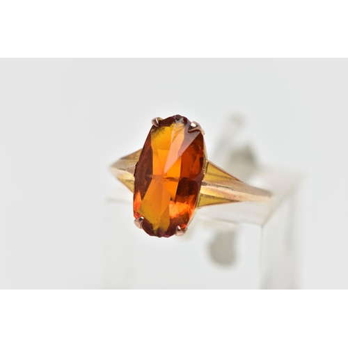 44 - A YELLOW METAL PASTE SINGLE STONE RING, the fancy shape orange paste claw set, to the tapered should... 