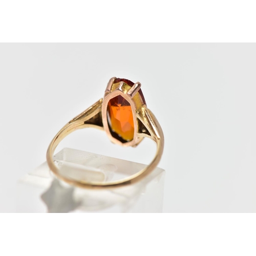 44 - A YELLOW METAL PASTE SINGLE STONE RING, the fancy shape orange paste claw set, to the tapered should... 