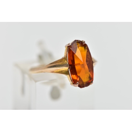 44 - A YELLOW METAL PASTE SINGLE STONE RING, the fancy shape orange paste claw set, to the tapered should... 