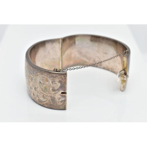 69 - A WIDE SILVER HINGED BANGLE, with a scrolling foliate design, fitted with a push button integrated b... 