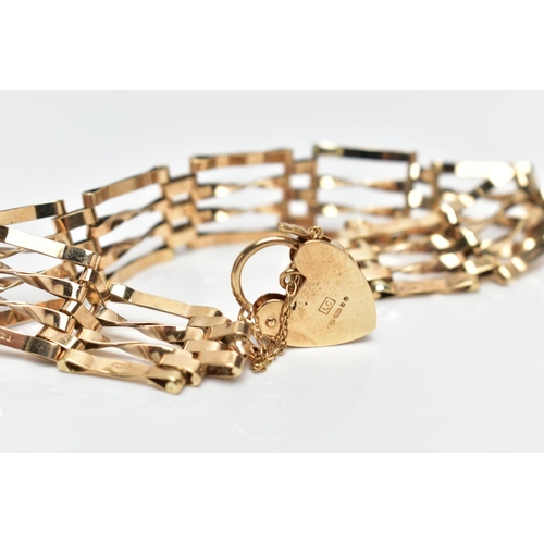 76 - A 9CT GOLD GATE BRACELET, four bar polished yellow gold gate bracelet, fitted with a heart padlock a... 