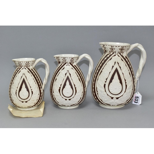 533 - THREE NINETEENTH CENTURY COBRIDGE CASHMERE GRADUATING JUGS, having cream on dark brown moulded folia... 