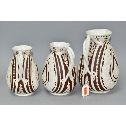 533 - THREE NINETEENTH CENTURY COBRIDGE CASHMERE GRADUATING JUGS, having cream on dark brown moulded folia... 