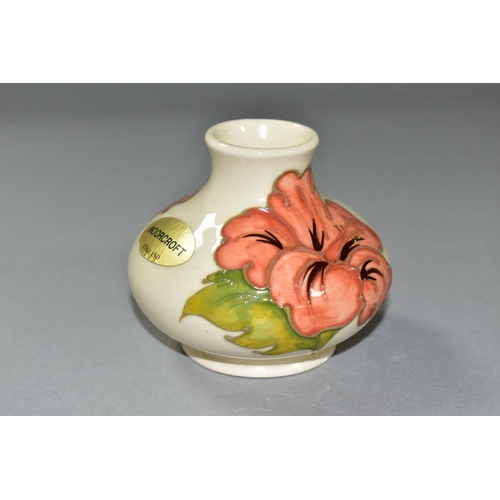 586 - A SMALL MOORCROFT ORANGE HIBISCUS PATTERN VASE, of squat baluster form, foil label to the side, appr... 