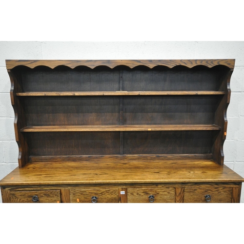 1224 - A REPRODUCTION OAK DRESSER, with a two tier plate rack, four drawers, and four panelled cupboard doo... 