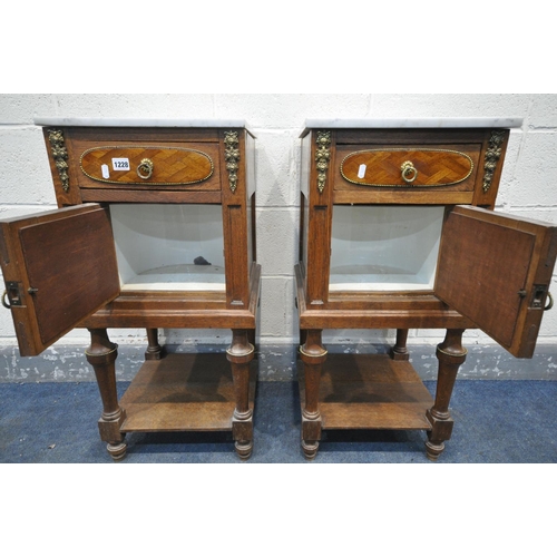 1228 - AN OPPOSING PAIR OF EARLY 20TH CENTURY OAK FRENCH POT CUPBOARD/BEDSIDE CABINETS, with marble top, br... 