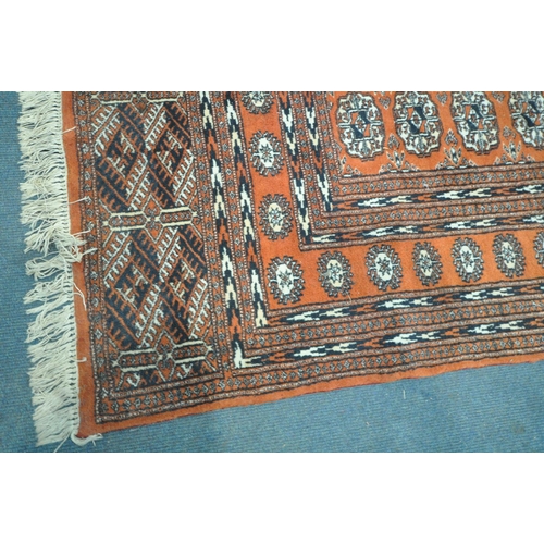 1255 - A 20TH CENTURY TEKKE ORANGE GROUND RUG, with a multi strap border, and twenty six medallions, 251cm ... 